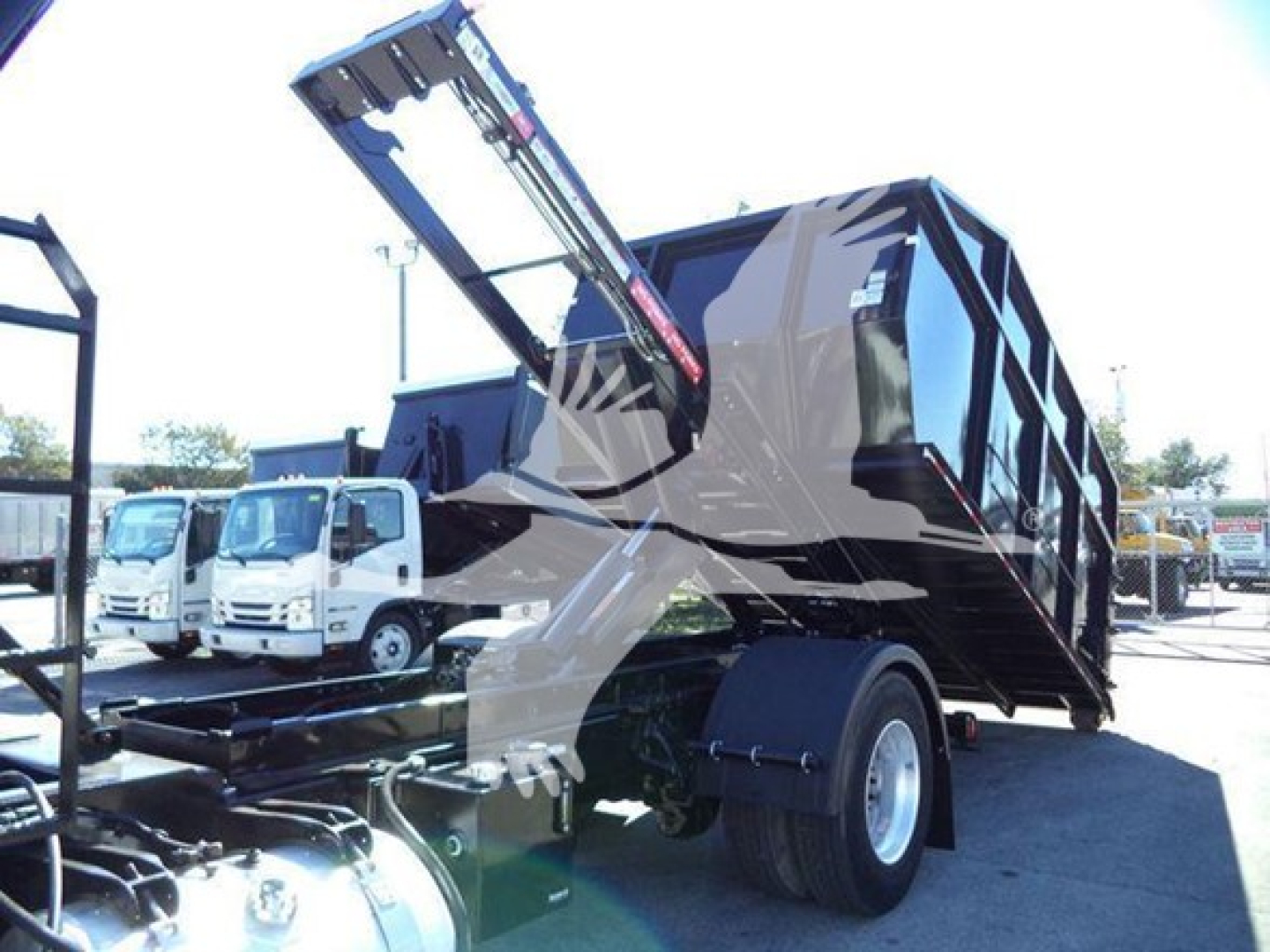 Peterbilt 337 roll-off truck with hydraulic lift arm and empty dump bed, side view showing rear dual tires and chassis.
