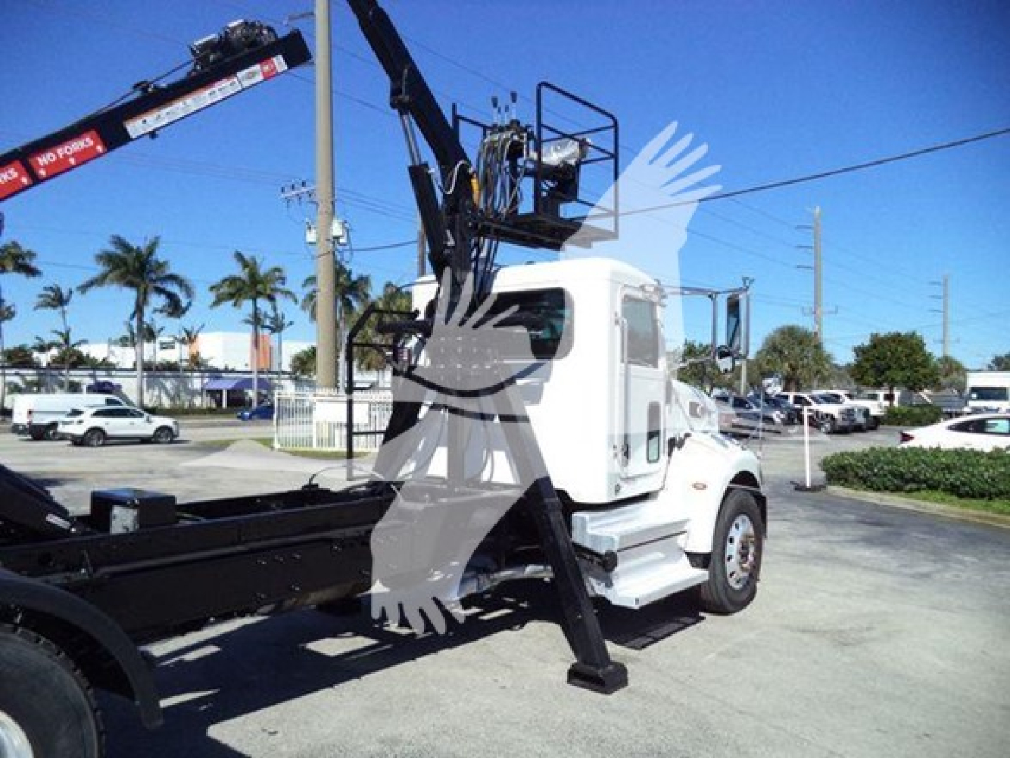Peterbilt 337 roll-off truck with crane in a parking lot, white cab, black crane arm, no visible text on the vehicle