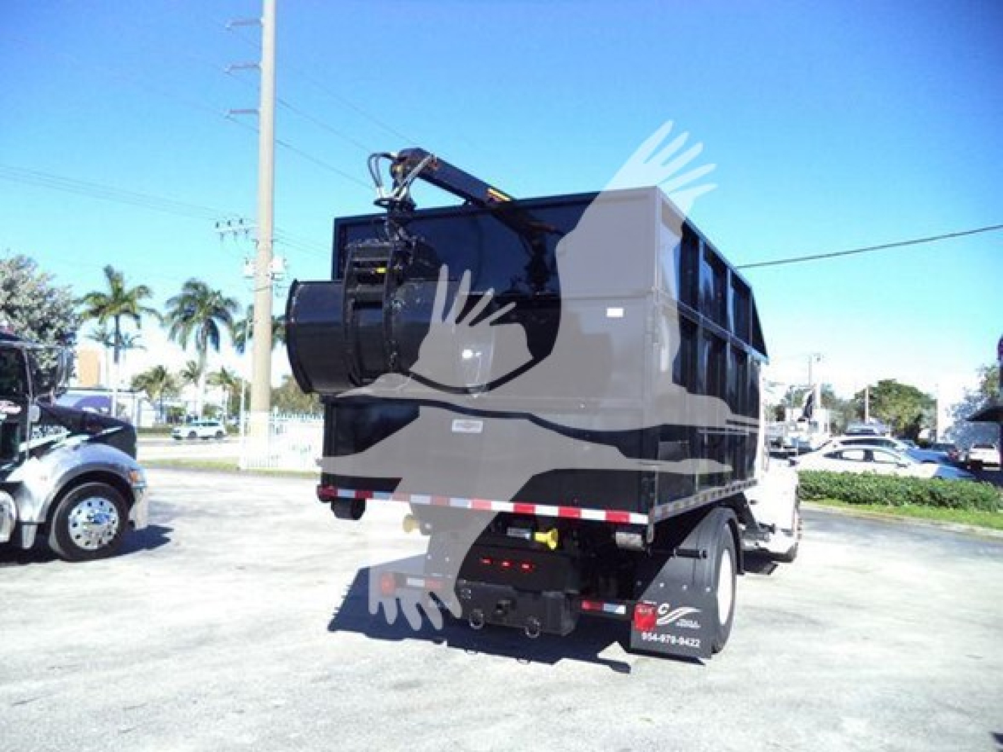 Peterbilt 337 roll-off truck rear view showing hydraulic crane arm and dump container, tail lights, and rear bumper.