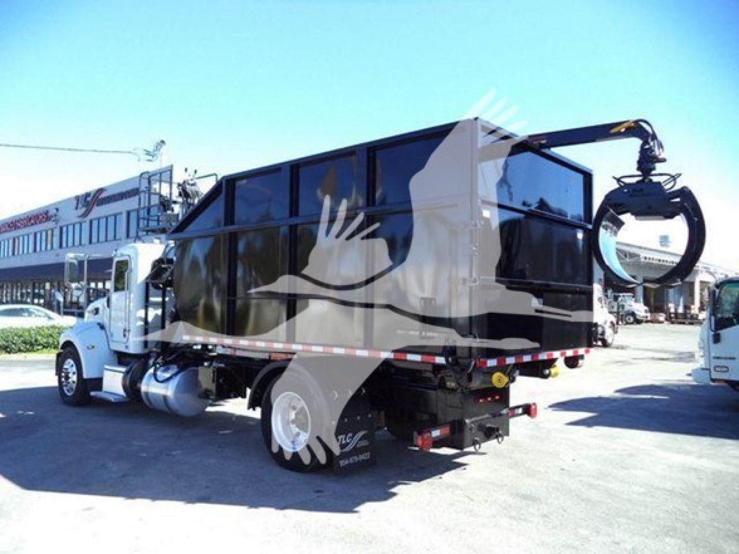 Peterbilt 337 rolloff truck in service with mounted waste container and hydraulic crane at rear.