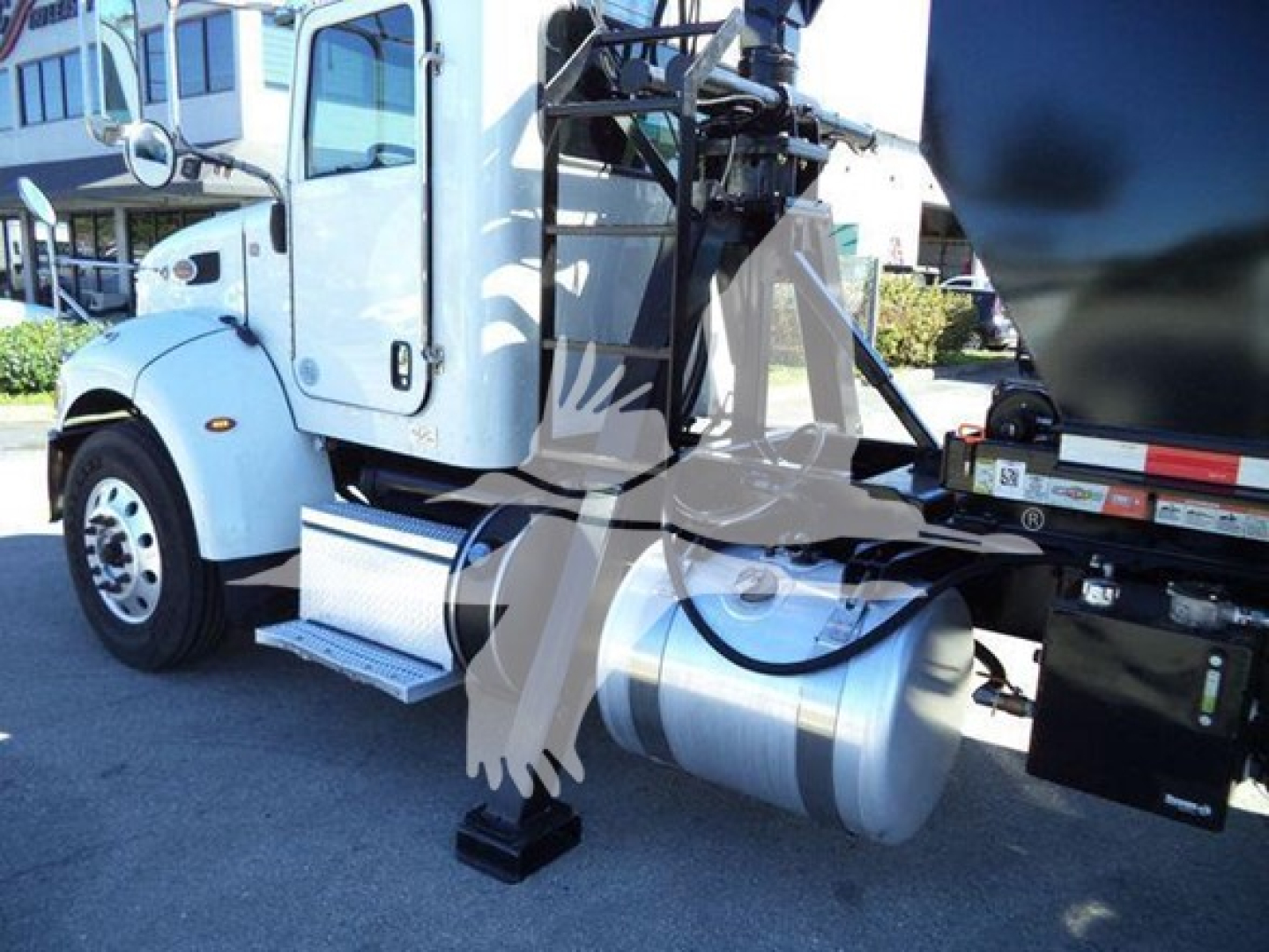Peterbilt 337 cab and fuel tank with chrome exhaust and hydraulic components visible on roll-off truck.