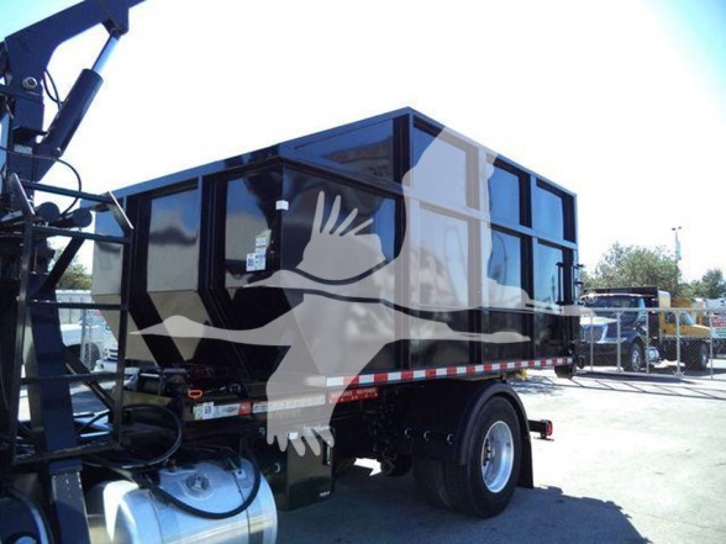 Truck cab and dump body mounted on trailer showing rolloff container and chassis with wheels.