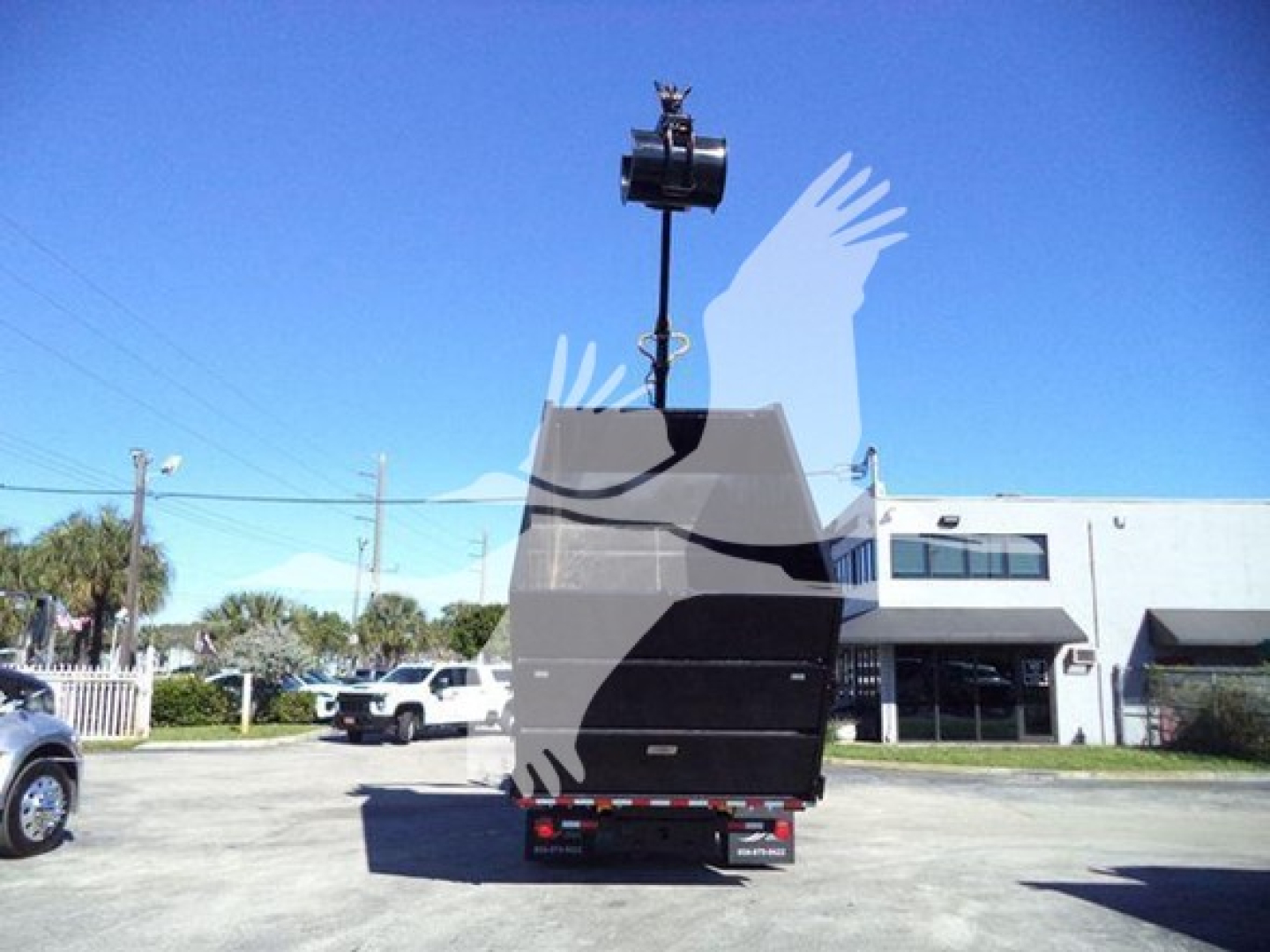 Peterbilt 337 roll-off truck back view showing tail area and hoist arm in raised position.