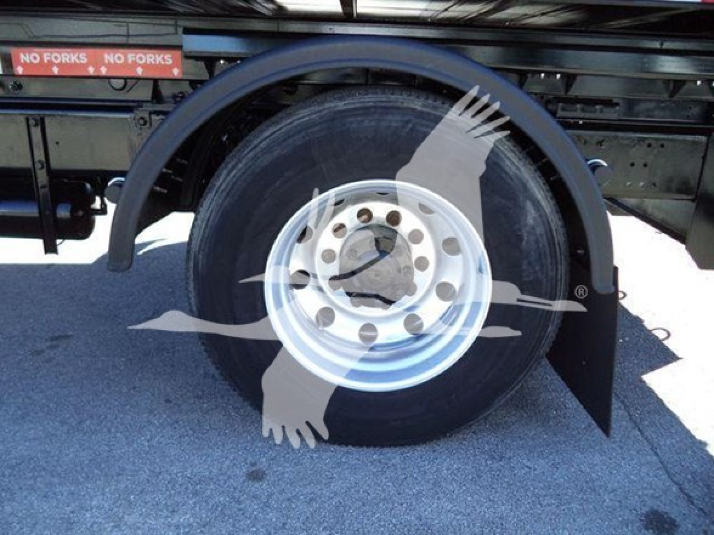 Peterbilt 337 wheel and fender area on a rolloff truck showing a single rear tire with hub and mudflap, part of the wheel well and undercarriage.