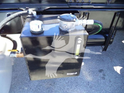 Peterbilt 337 truck underside showing a black rectangular fuel/auxiliary tank with metal fittings and hoses.