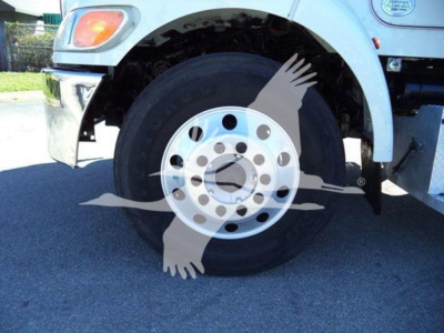 Front wheel of a Peterbilt truck showing a silver steel rim with circular holes and a black tire.