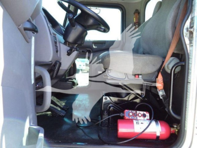 Peterbilt 337 interior cab view showing driver seat, steering wheel, dashboard, and a red fire extinguisher mounted on the floor near the seat; no other text visible.