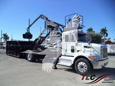 Peterbilt 337 roll-off truck with hydraulic crane in-service showing front and side view with load bed and branding.