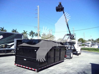 Peterbilt 337 roll-off truck with a raised hydraulic idler and dumping container in a yard.