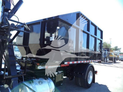 Peterbilt 337 roll-off truck rear quarter with black dump body, dual rear wheels, and hydraulic lift mechanism visible.