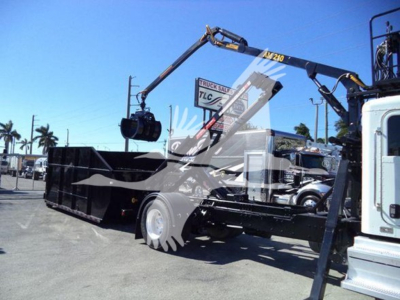 Peterbilt 337 rolloff truck with crane arm in service side view showing loader bed and hydraulic arm.