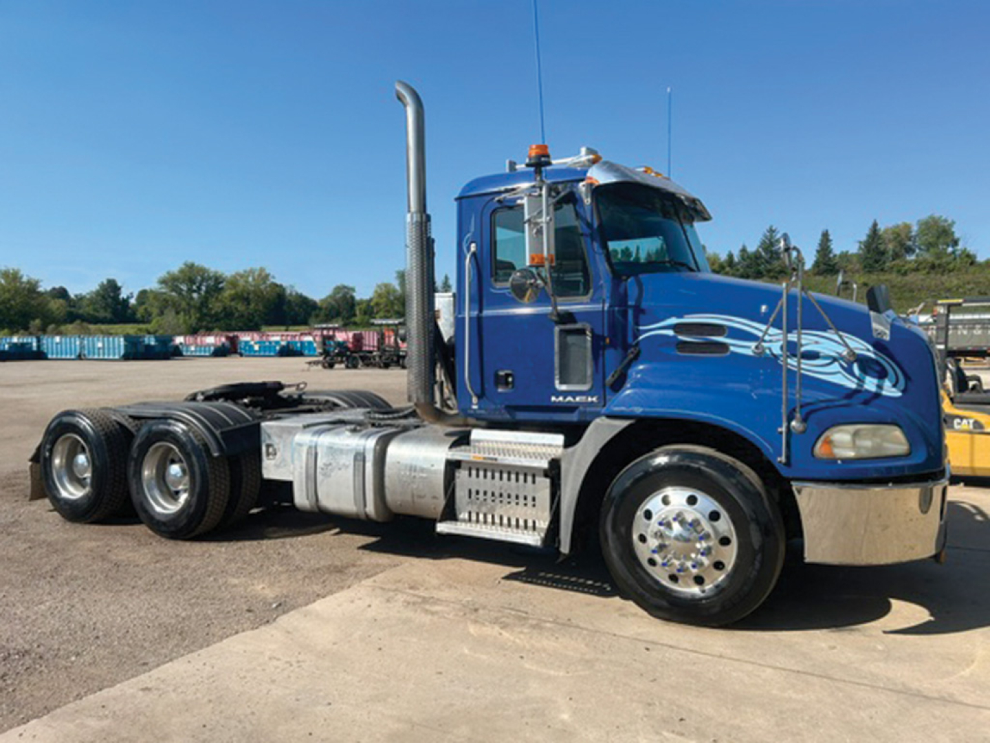 Blue 2014 Mack CXU613 conventional daycab truck side view showing chrome fuel tanks and exhaust stack.