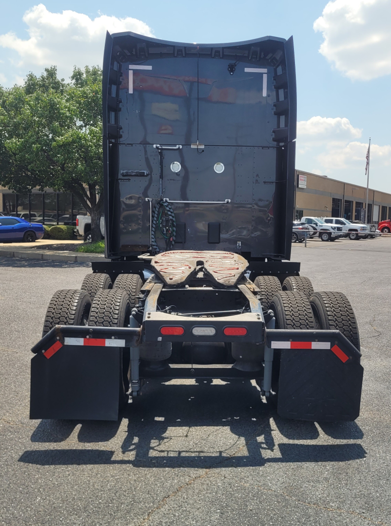 Truck rear view of a 2022 Peterbilt 579 tractor chassis showing fifth wheel, dual rear axles, mud flaps, and rear bumper; no cab visible.