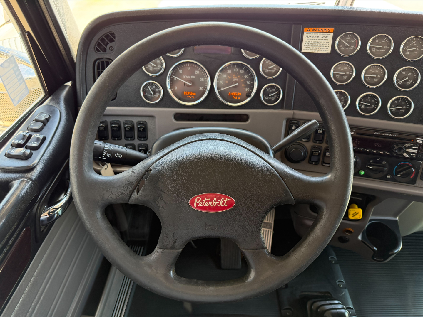 Peterbilt 389 interior with steering wheel and instrument cluster showing gauges and controls.