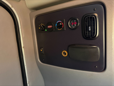 Peterbilt 389 cab interior panel showing HVAC controls, round gauges, and a vent.