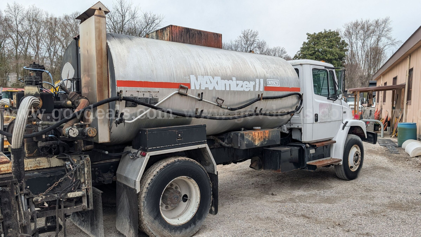 Tank truck showing MAXimizer II tank and chasis of Freightliner FL70, white cab, metal tank, hoses and fittings visible.