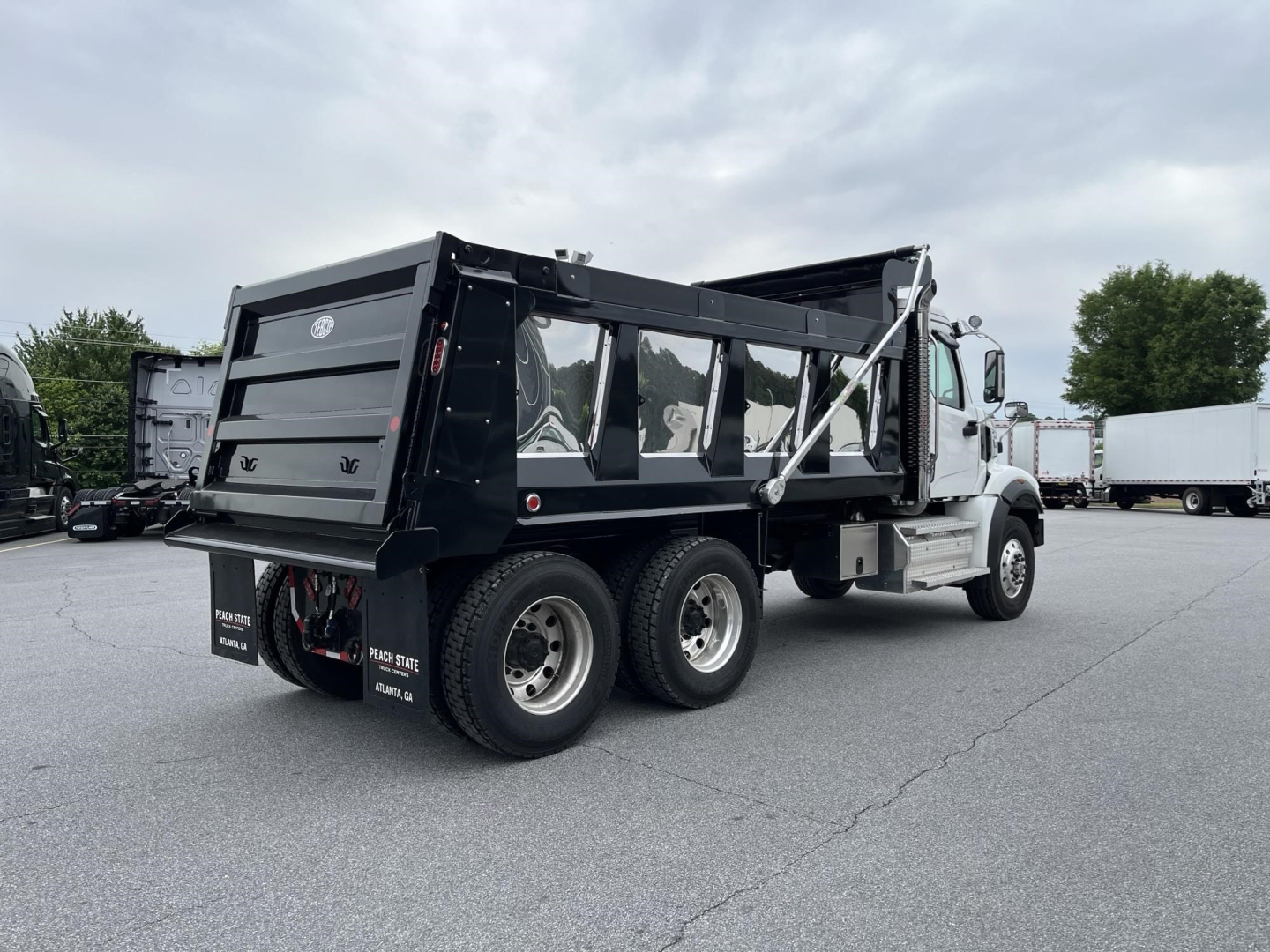 Western Star dump truck with black dump body and dual rear axles, side view showing cargo bed and wheels.