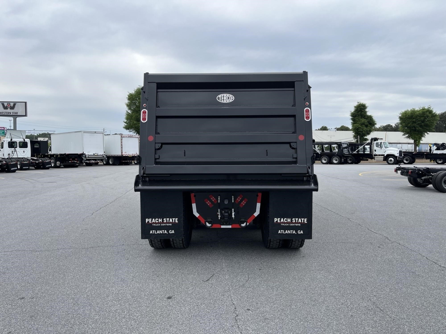 Dump truck bed rear showing Western Star logo and tailgate, black dump truck with dual tail lights, Peach State Atlanta GA mud flaps.