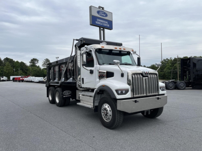 Dump truck in a dealership lot, 2027 Western Star 47X, white cab, black dump body, front grille, stock number 342827 visible.