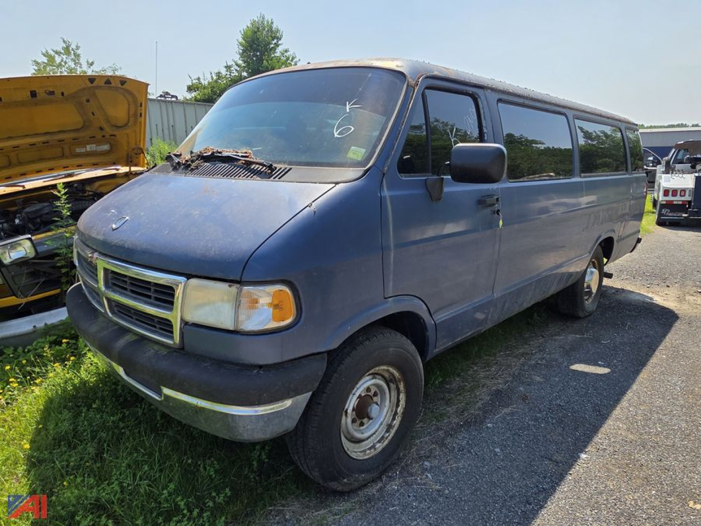 Dodge Ram van cargo van in blue, side view, showing front grille with dodge emblem and headlights; windshield wipers on hood, wheel wells, and passenger sliding side windows visible.