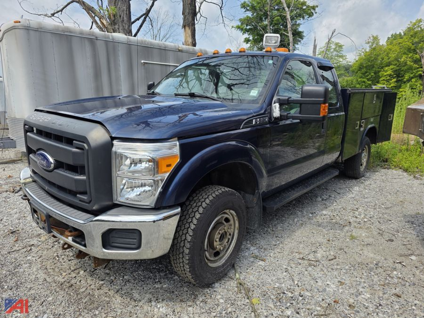 Ford F-250 Super Duty pickup with utility bed, dark blue, crew cab, dual rear wheels, on gravel lot.