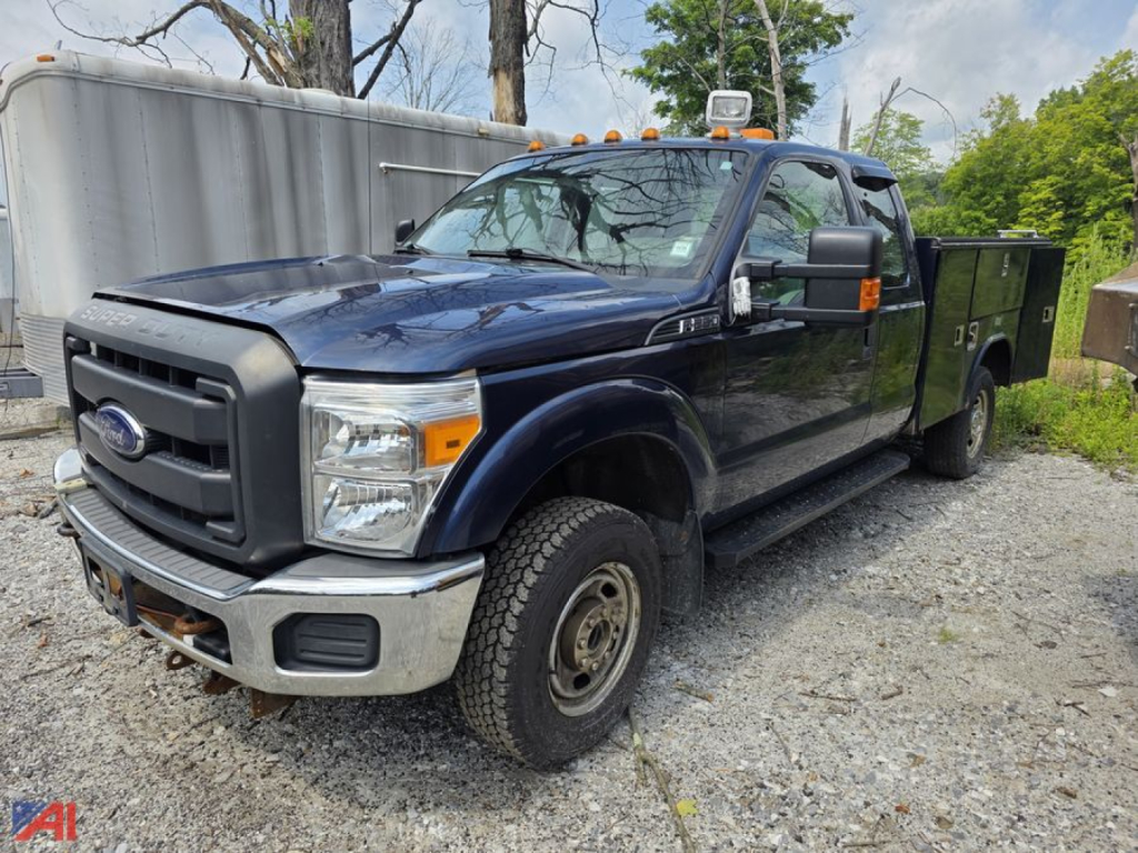 Ford F-250 Super Duty pickup with utility bed, dark blue, crew cab, dual rear wheels, on gravel lot.