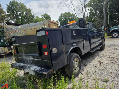 Utility body pickup truck rear and side view showing black service utility bed with storage compartments on Ford F-250 Super Duty, 2014 model year, 4x4, with orange caution light and spare tire mounted on top.