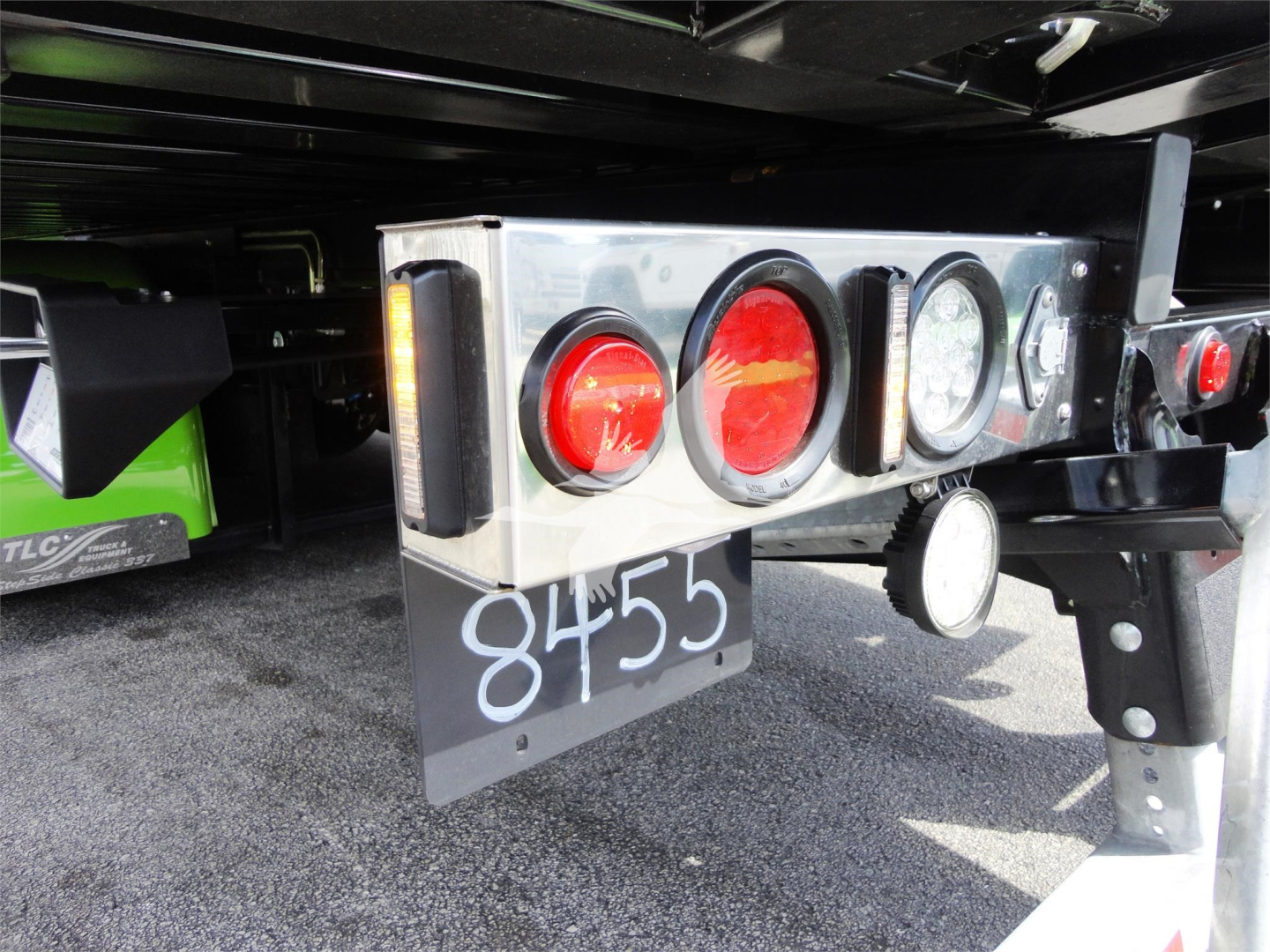Rear of a 2022 Peterbilt 337 rollback truck showing taillights, license/stock number '8455' on a dark mudflap, metal bumper, and hitch area.