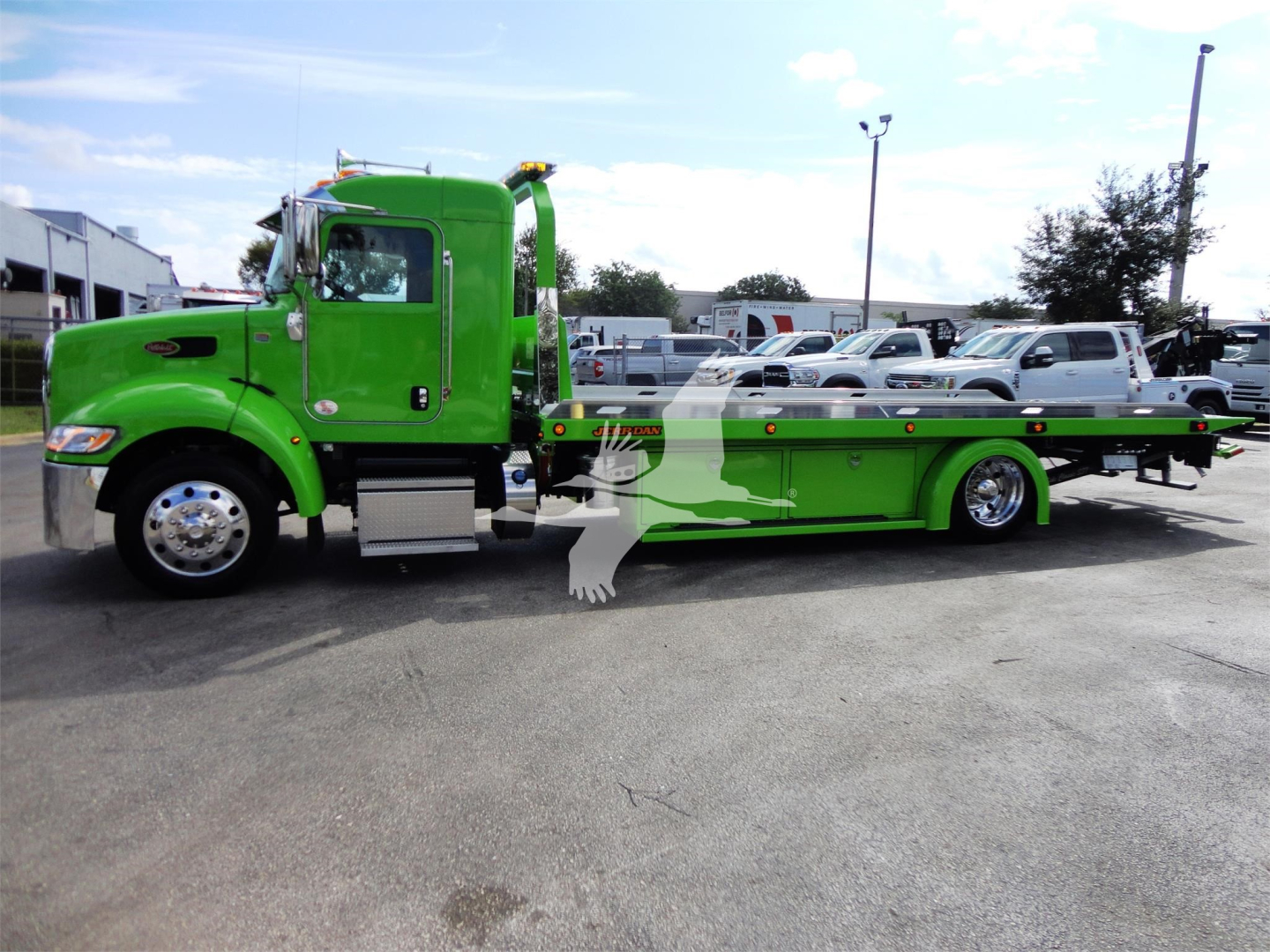 Green 2022 Peterbilt 337 rollback truck side view with flatbed and chrome wheels.