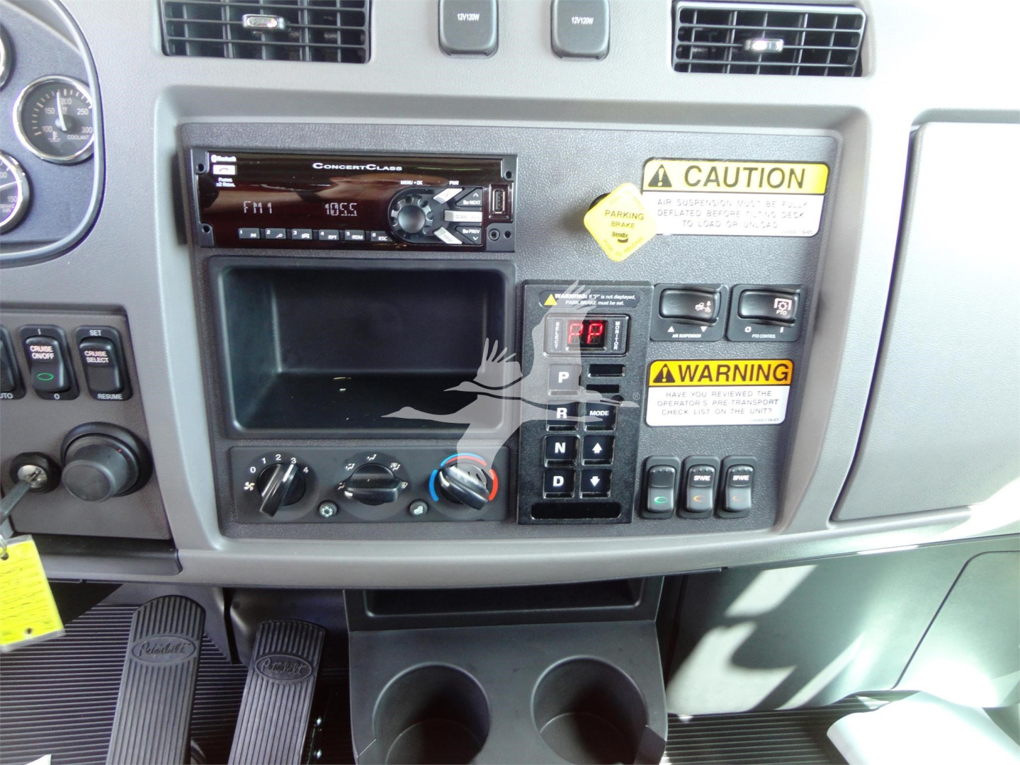Peterbilt 337 dashboard with aftermarket stereo, climate controls, cup holders, and warning labels visible.
