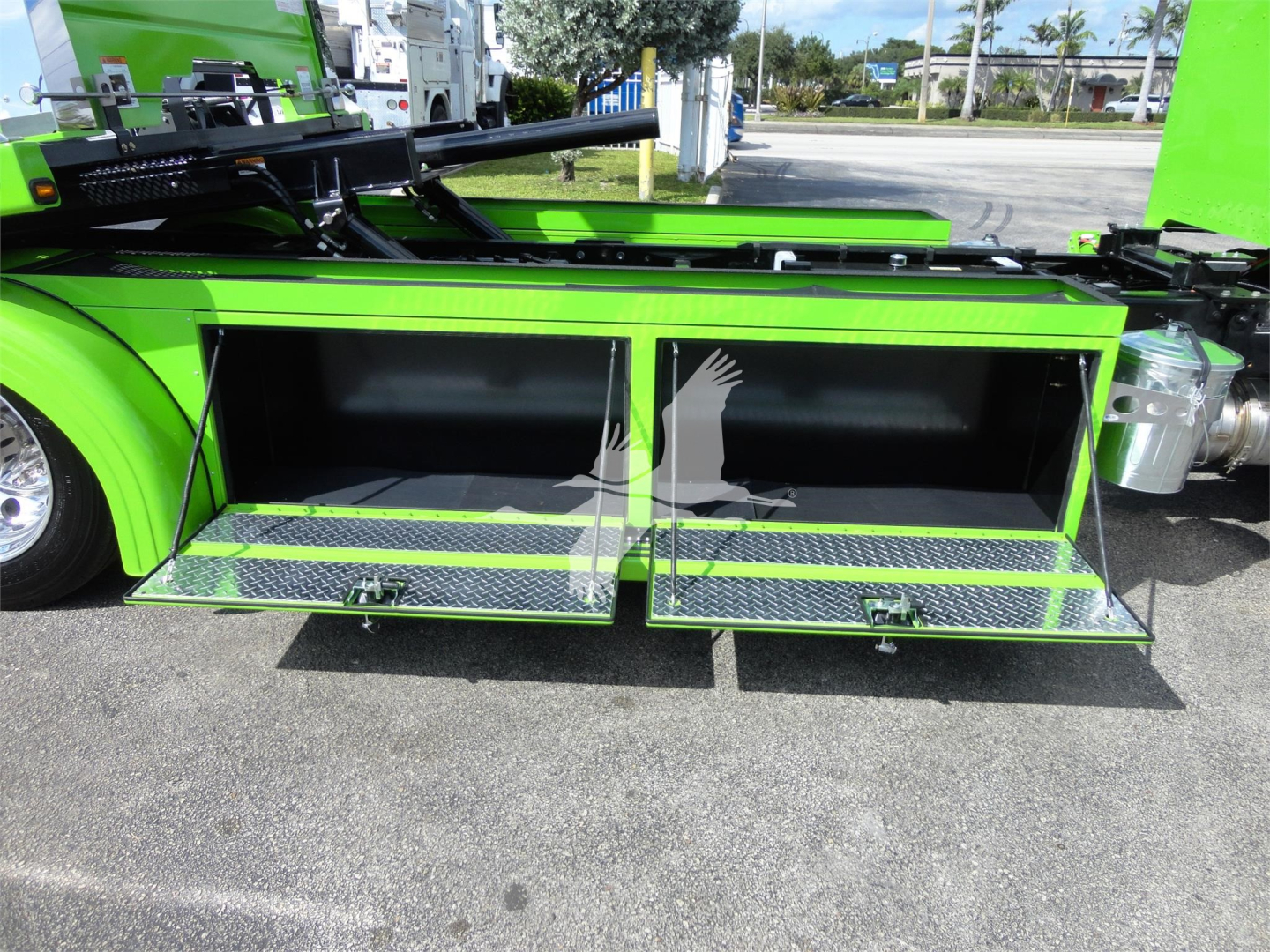 Peterbilt 337 rollback truck side storage compartments open showing two large rectangular toolboxes with diamond plate steps and bright green exterior.