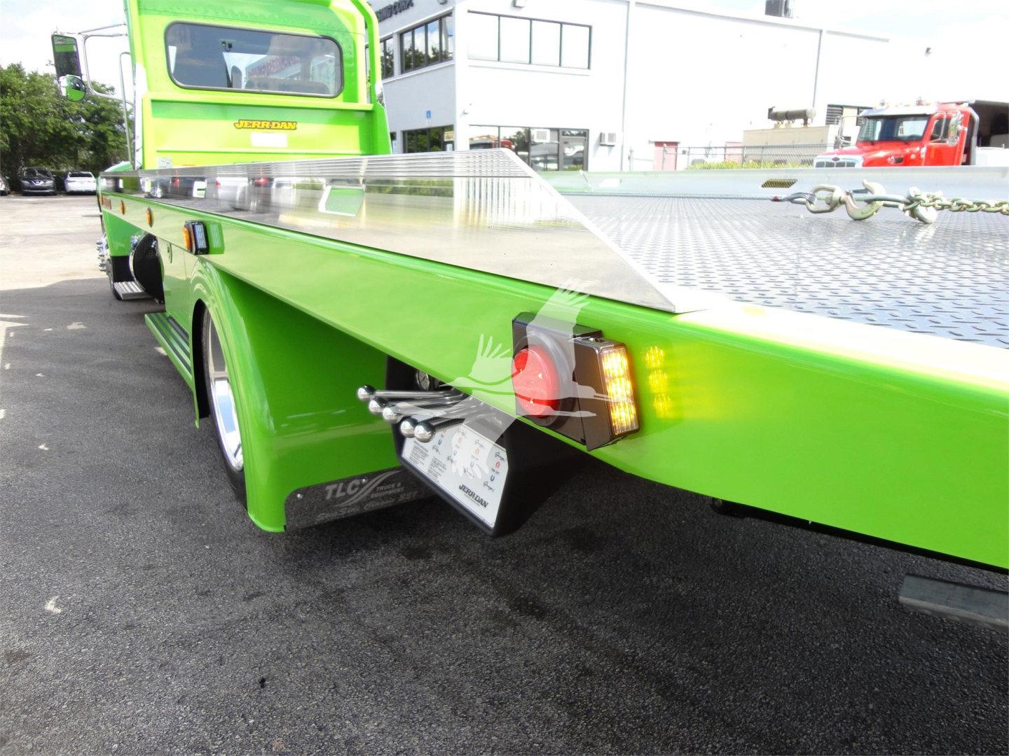 Peterbilt 337 rollback truck rear left side showing bright green flatbed with diamond plate surface and taillight assembly.
