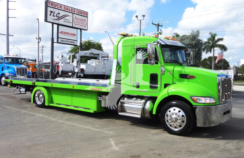 Green Peterbilt 337 rollback tow truck in a dealership lot with flatbed extended.