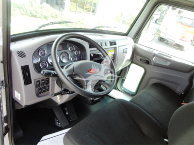 Peterbilt 337 cab interior showing steering wheel and dashboard gauges, driver seat, and entry area with pedals and controls.
