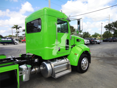 Green Peterbilt 337 cab at side view showing chrome fuel tank and steps, with rollback truck body and rear wheels visible.