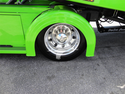 Green Peterbilt truck fender and chrome wheel with polished hub showing bright green body and black tire.