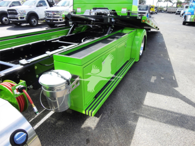 Green Peterbilt 337 rollback bed with crane chassis and hydraulic lines, side view showing painted dove logo and black pinstripe accents.