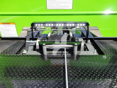 Trucks equipment bay with winch/lock mechanism and LED light bar on a green Peterbilt 337 rollback truck showing mounting hardware and diamond plate surface.