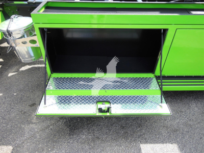 Green Peterbilt 337 rollback truck rear storage compartment open, diamond plate step, stock number J47210, chrome fuel/air canister visible on left.