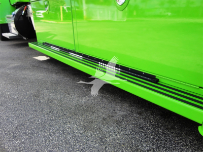 Side view of a bright green Peterbilt 337 truck with black side steps and lower running boards, showing the lower door area and ground.