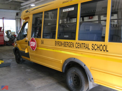 Ford E-Series bus showing Byron-Bergen Central School label and stop sign, side view with wheelchair lift access area visible.