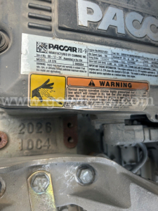 Label plate on Pacar/Paccar engine showing model and warning, with serial numbers and a rusted bolt area.