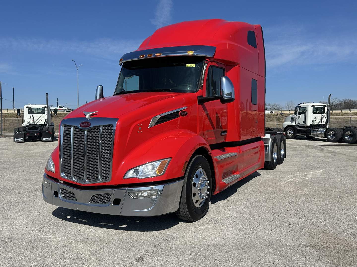 Red 2023 Peterbilt 579 tractor truck with sleeper cab, front grille, chrome bumper, and dual rear axles. Visible text includes Peterbilt logo on grille and chrome mirrors.