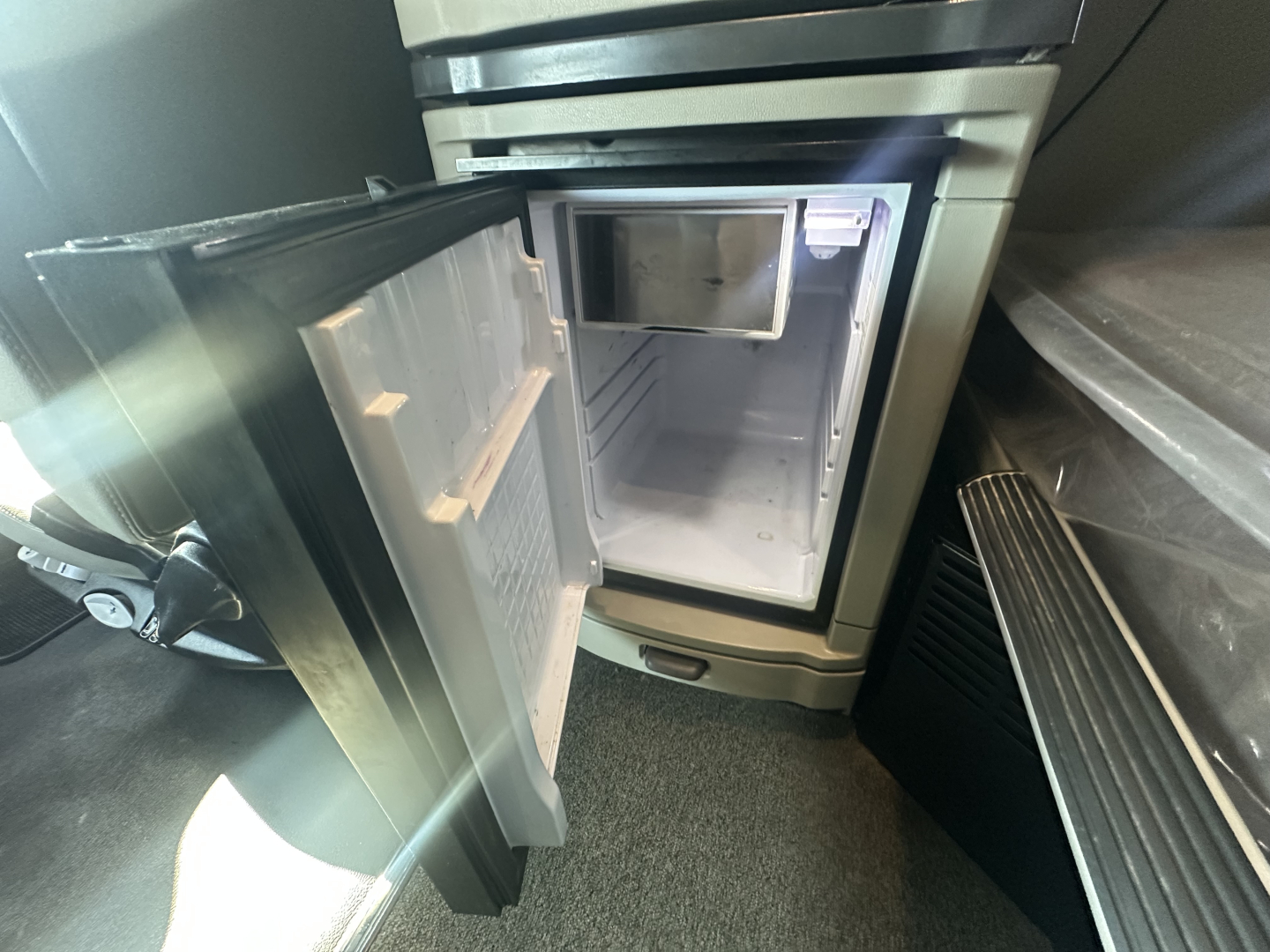 Refrigerator/freezer compartment of a Peterbilt 579 truck interior showing open small freezer door with empty interior.