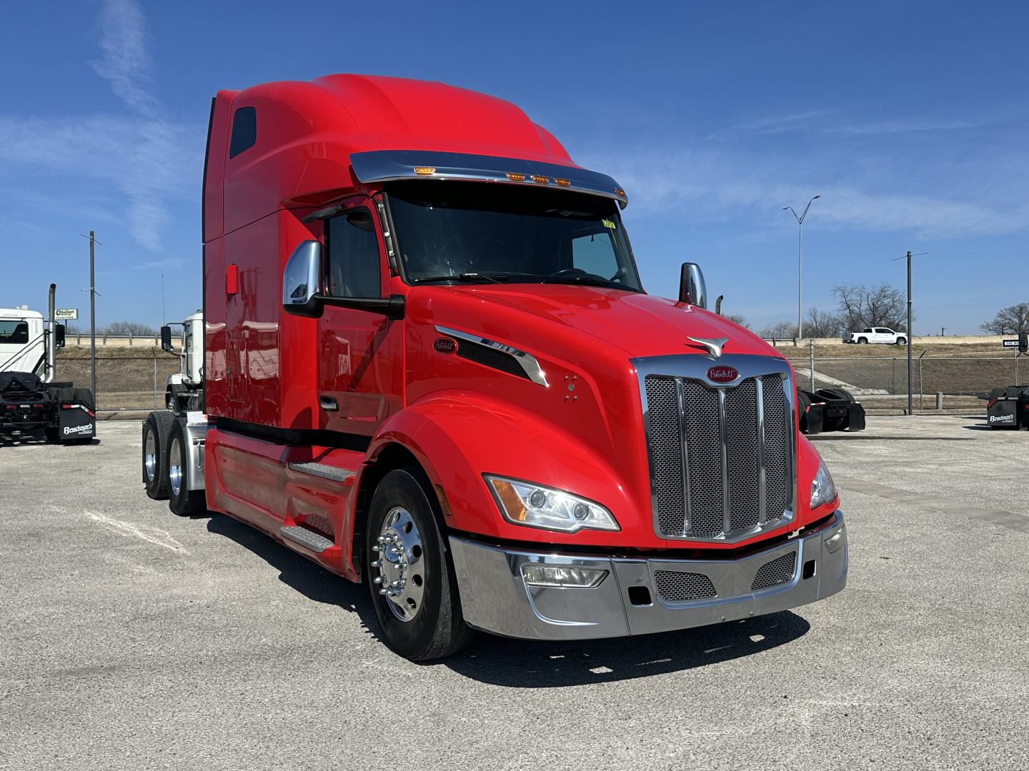 Peterbilt 579 truck in red, front-angled view showing tall sleeper cab, chrome grille, headlights, and bumper.