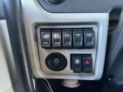 Peterbilt 579 cab dashboard controls panel with multiple switches and 12V socket, circular power outlet, illuminated warning icons.