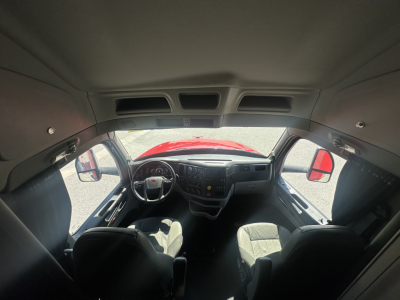 Peterbilt 579 interior cab view from front with dashboard and steering wheel; driver and passenger seats visible; red hood through windshield.