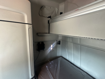 Peterbilt 579 truck sleeper cab interior showing upper bunk shelf and wall panel with power outlet and wiring.