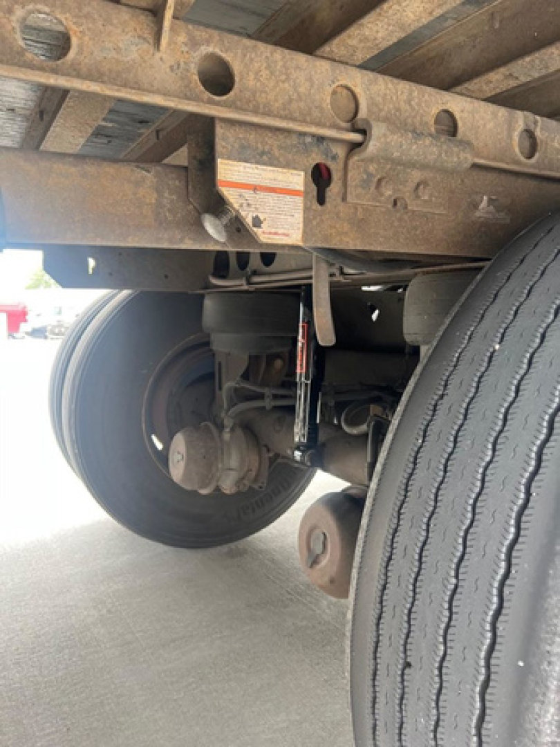 Trailer undercarriage showing rear axle and suspension components of a used 2012 utility van trailer with dual wheels.