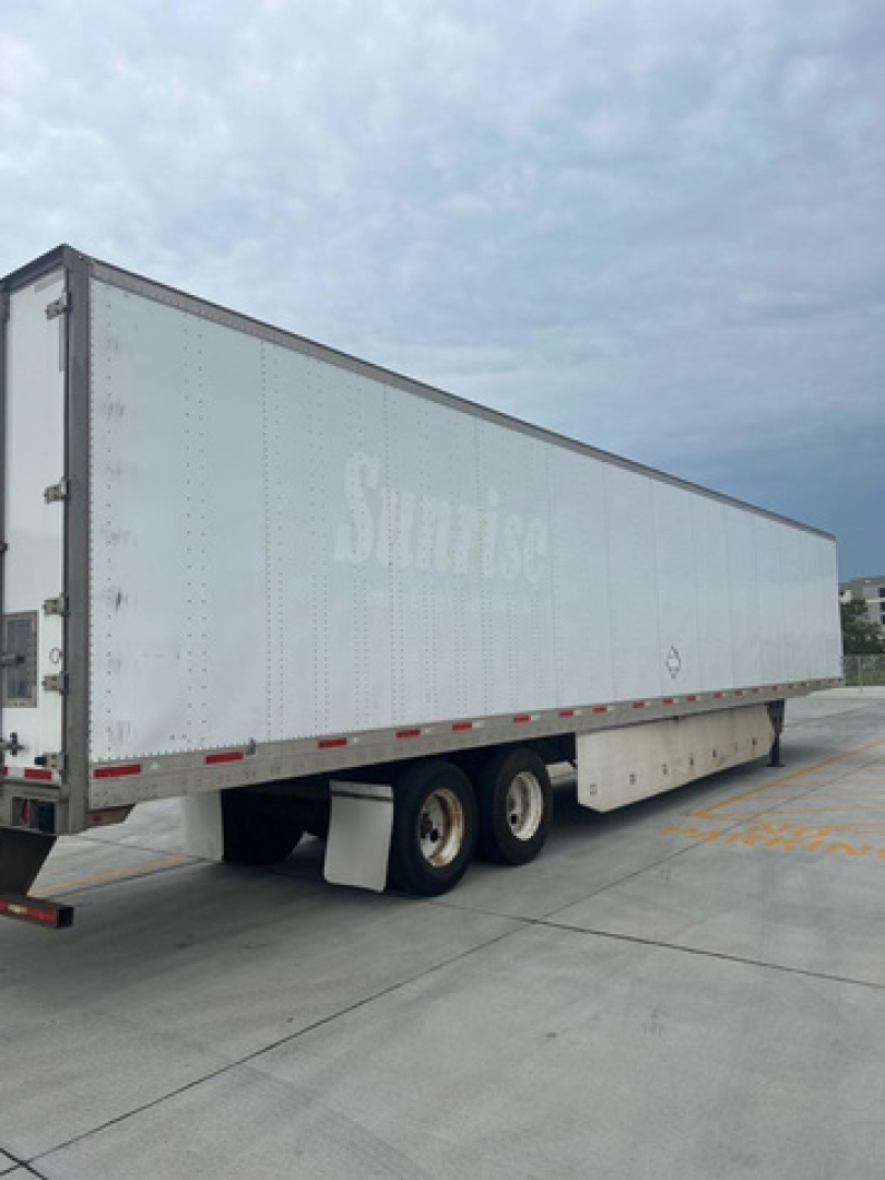 Box trailer with Sunise branding, side view, tandem rear wheels, white exterior, no visible text legible except faded 'Sunrise' on trailer side.